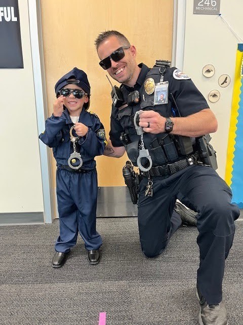 Career day, a student dressed as a police officer posing with a police officer.