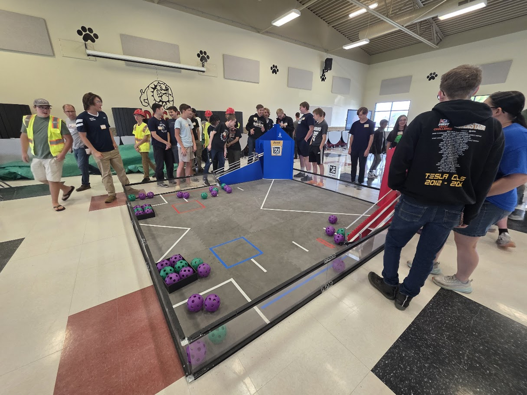 Group of people gathered around a robotics court