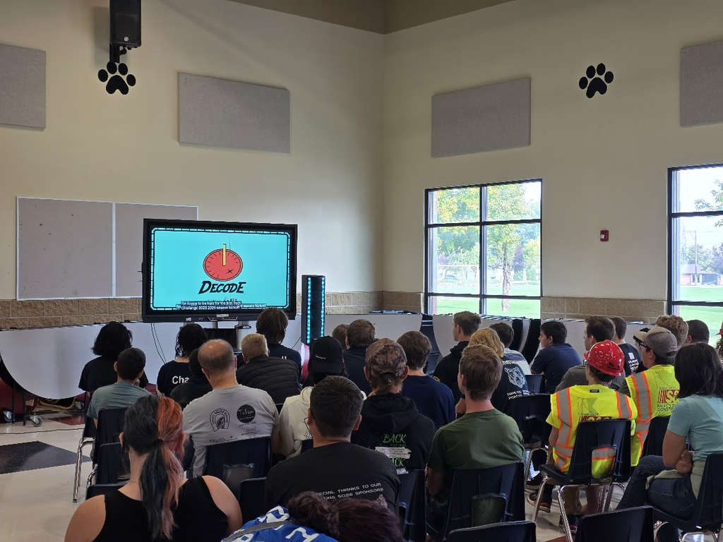 Group of people watching a TV with the word Decode on it