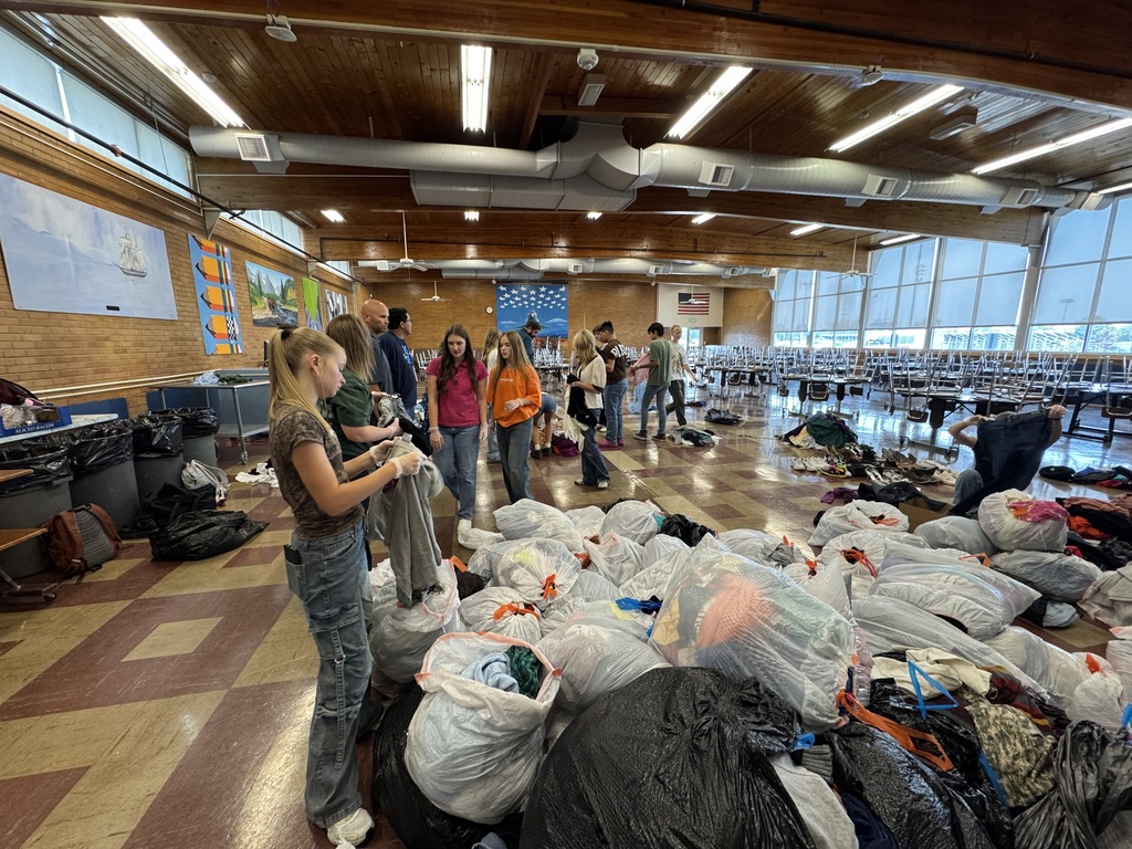 Students and teachers sorting trash bags full of clothes