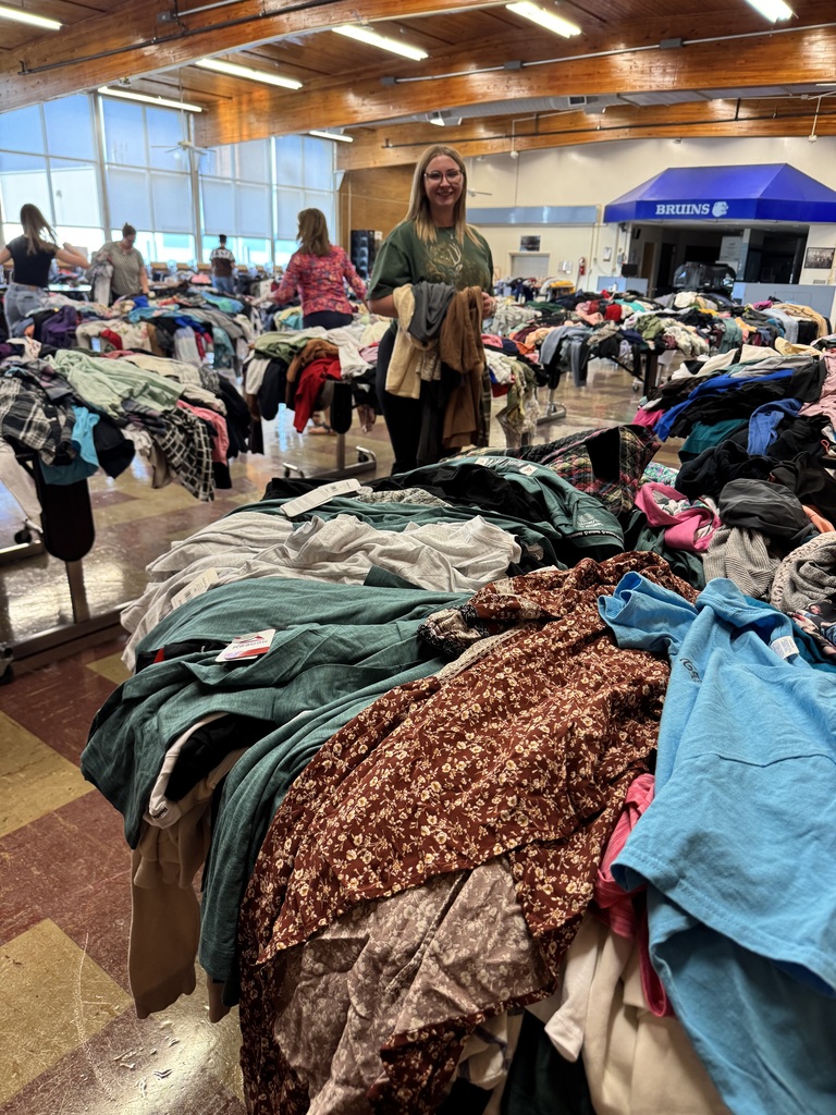 Girl standing in the middle of tables piled high with clothes