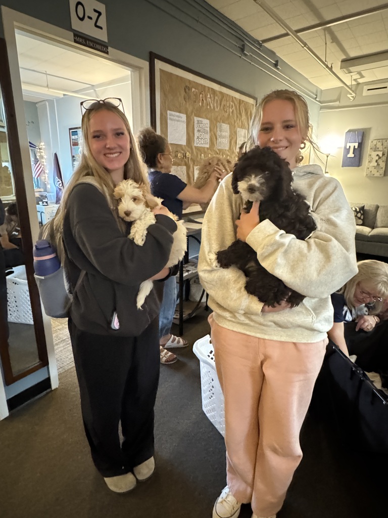 Two female students holden doodle puppies