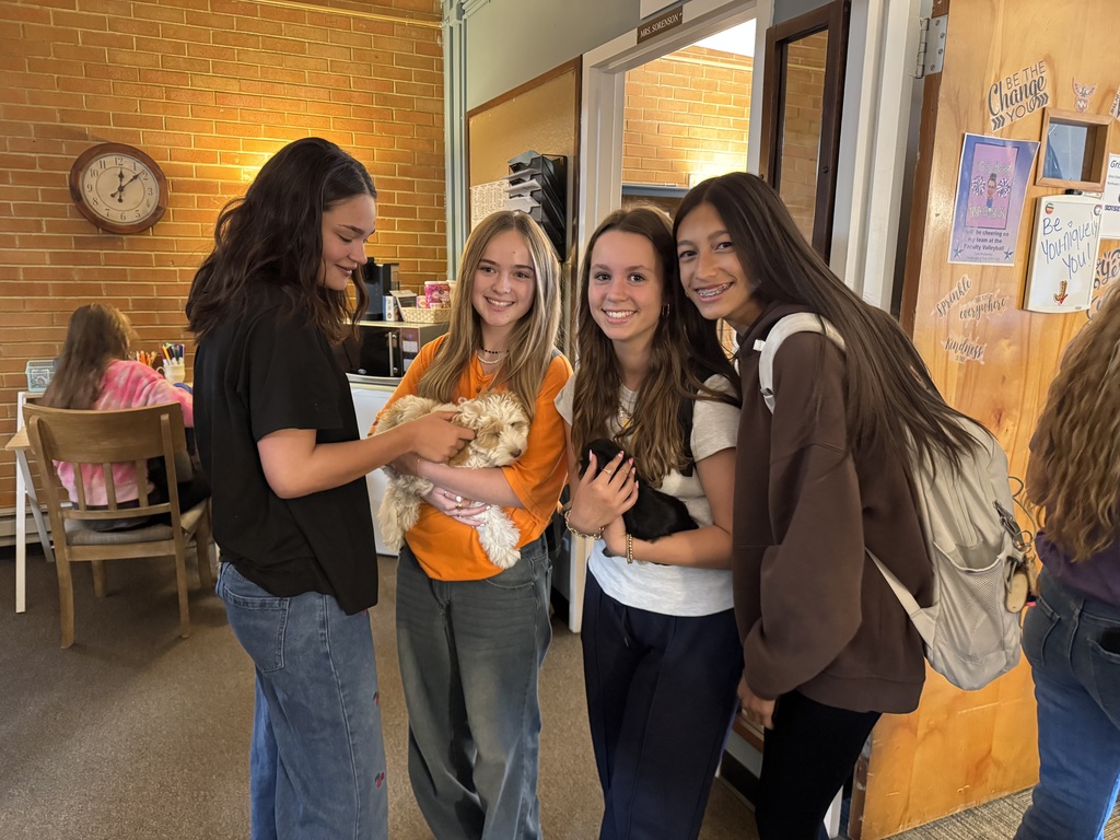 Group of female students posing with adorable puppies