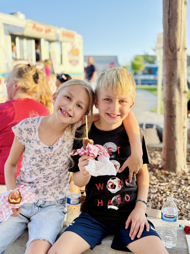kids eating corn dogs by a food truck