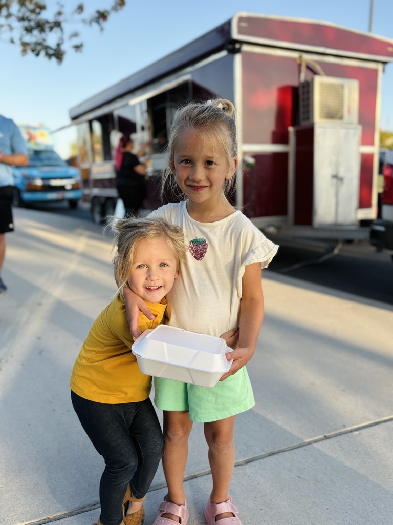 girls standing with food by a food truck