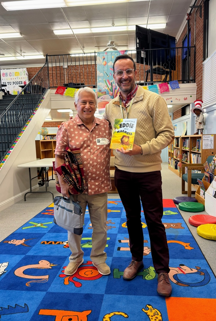 Two men standing together holding a book