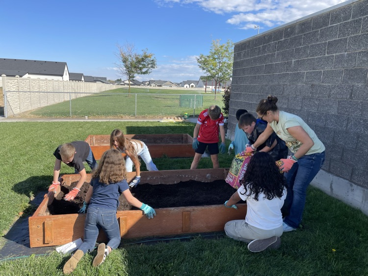 students filling a raised bed with soil