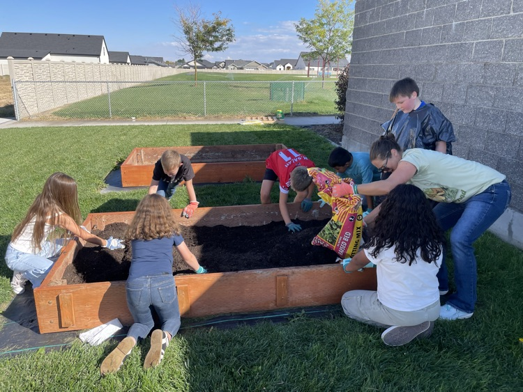 students filling a raised bed with soil