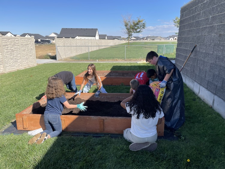 students filling a raised bed with soil
