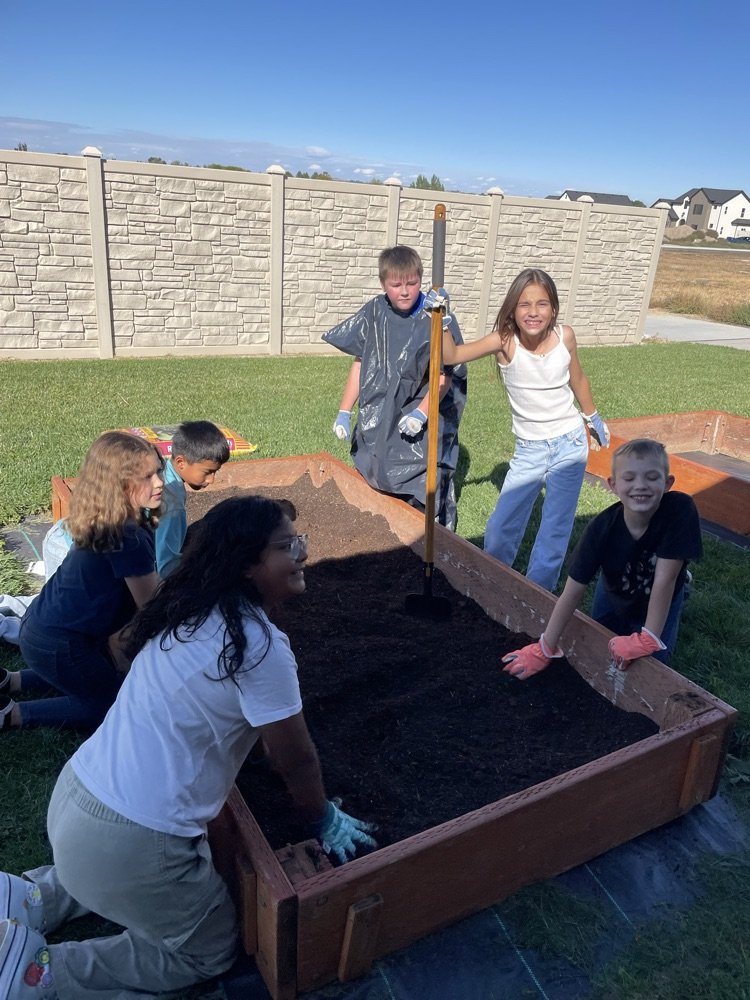 students filling a raised bed with soil