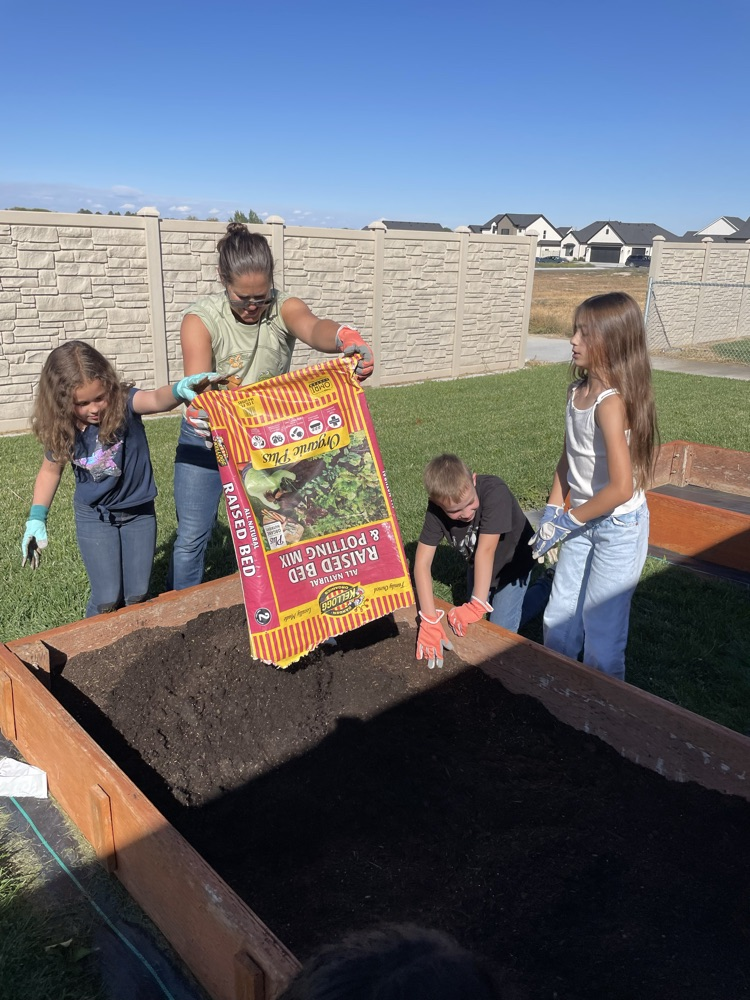 students filling a raised bed with soil