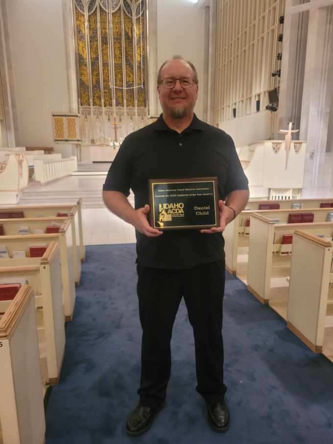 Man standing with a plaque in the middle of church pews