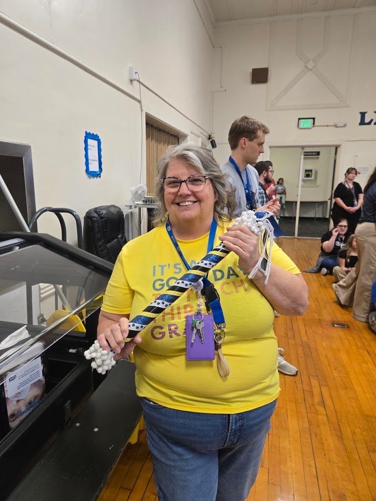Teacher at Lincoln holding the spirit stick after being rewarded at the assemply of leadership.