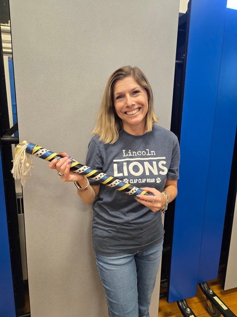 Teacher at Lincoln holding the spirit stick after being rewarded at the assemply of leadership.