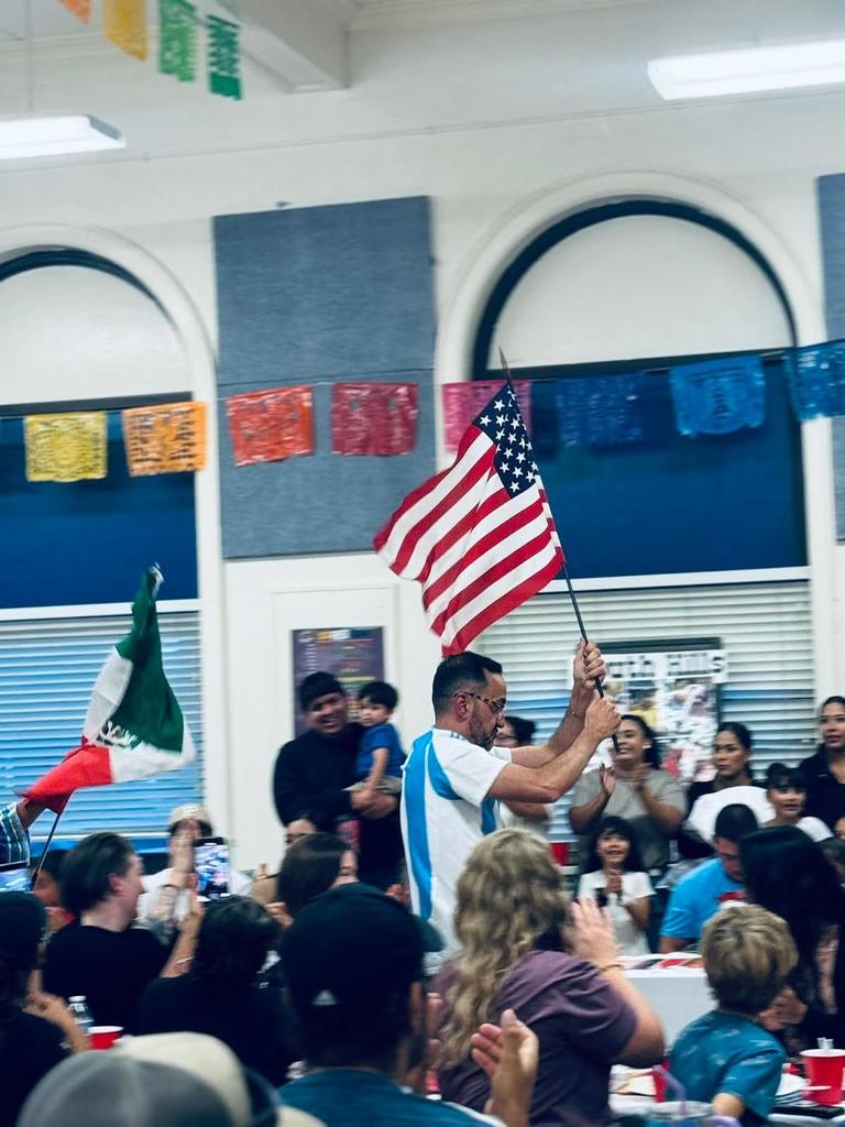 Families watching staff walk the American and Mexican flags.