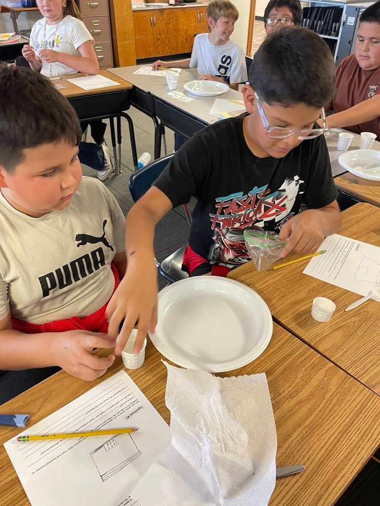 Harrison 5th graders mixing baking soda and vinegar to study gas pressure and chemical reactions.
