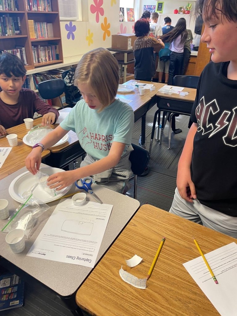 Harrison 5th graders mixing baking soda and vinegar to study gas pressure and chemical reactions.