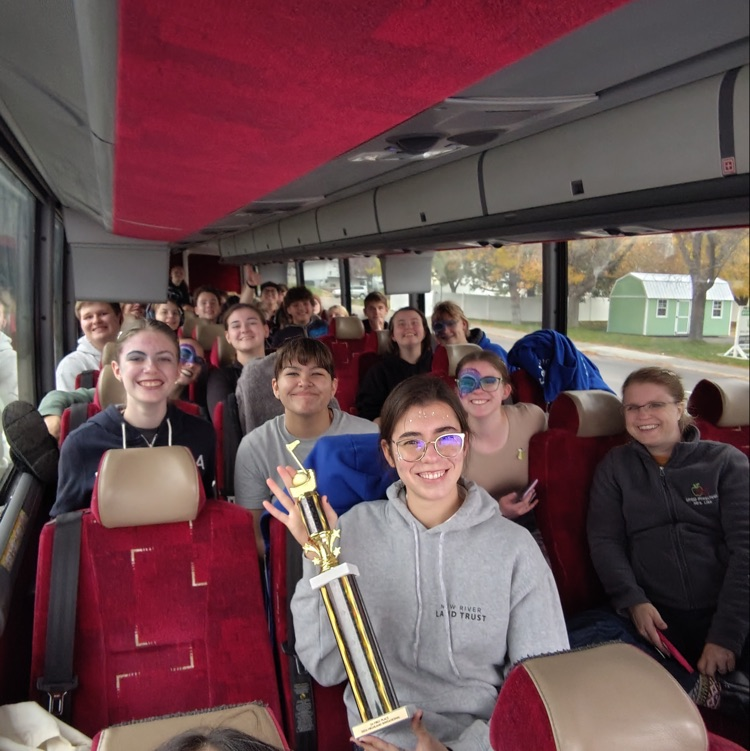 Band students sit on the bus with trophy in hand