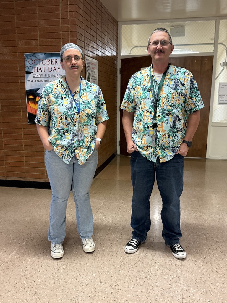 A picture of two staff members dressed alike. They are wearing Hawaiian shirts and jeans.