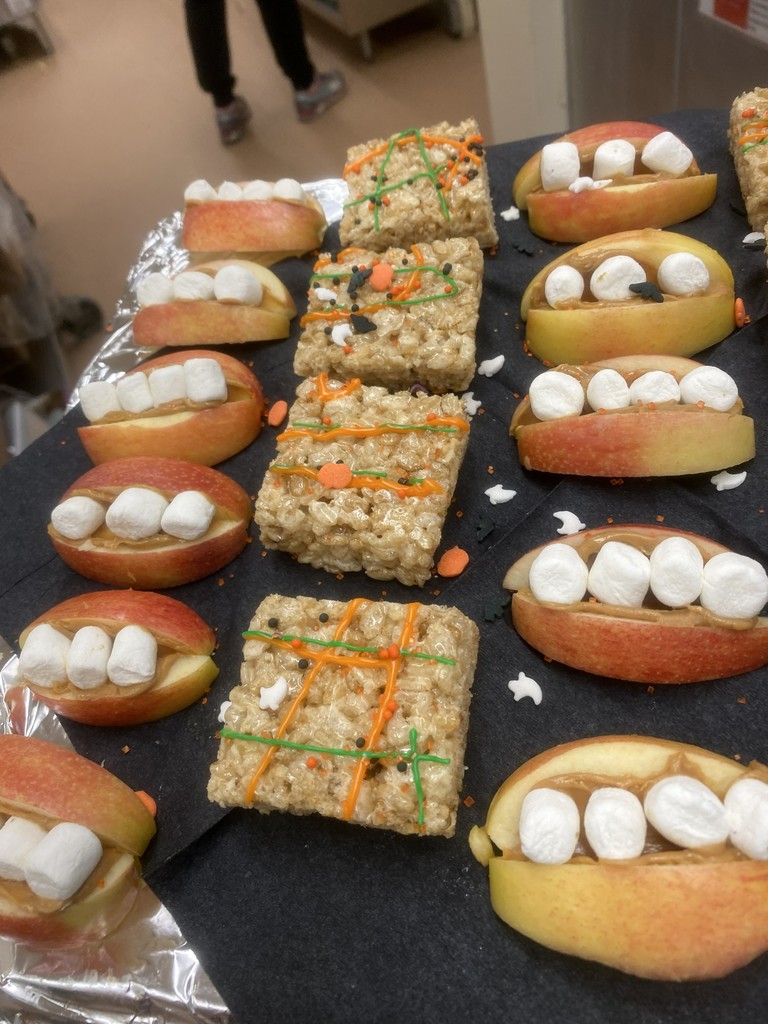 Rice Krispy treats with orange drizzled frosting and apples cut to look like a mouth with marshmallow teeth