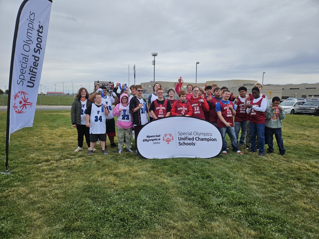 Unified sports athletes standing in jerseys and sweatshirts around a Unified Sports sign