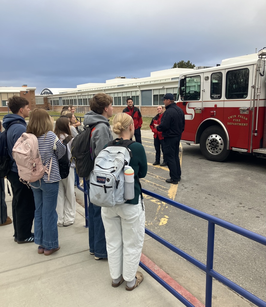 Students stand outside TFHS and listen to emergency responders in front of a fire truck. 