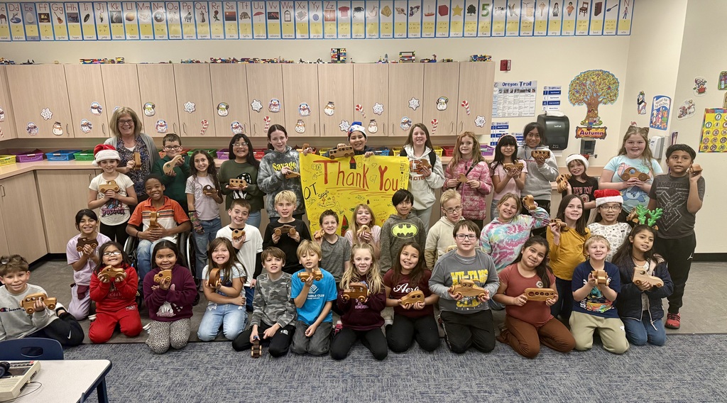 Students smiling together with donated wooden cars
