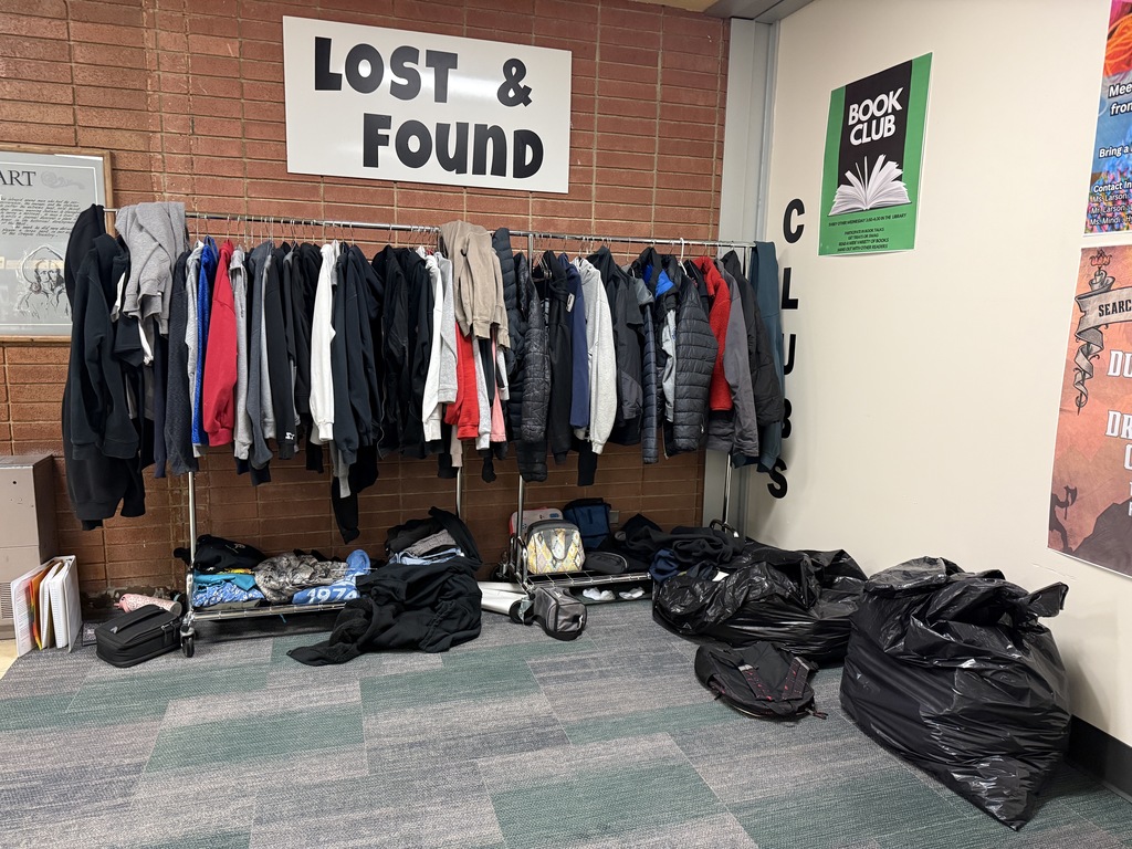 a picture of Lost & Found with clothes hanging on a rack and garbage bags filled clothes 