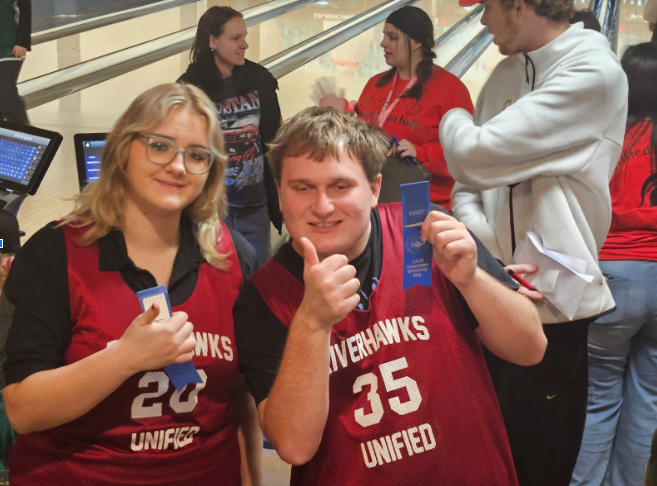 One female and one male student hold blue ribbons in one hand, showing a "thumbs up" with the other.