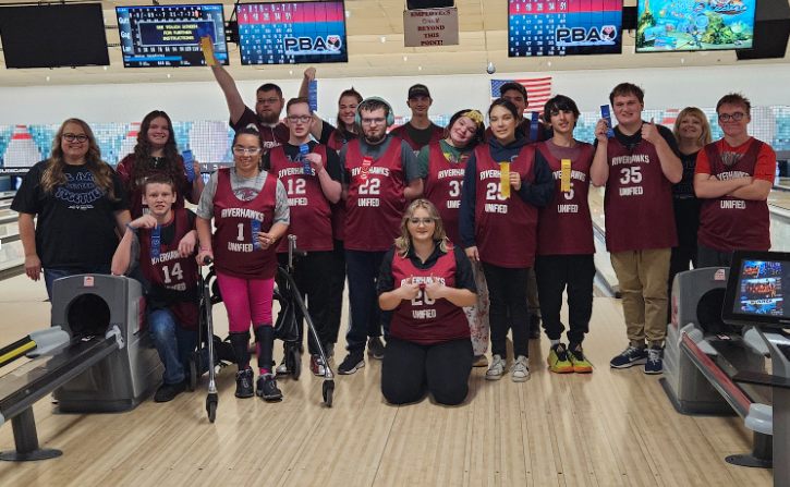 A group of high school students excitedly holding up ribbons.