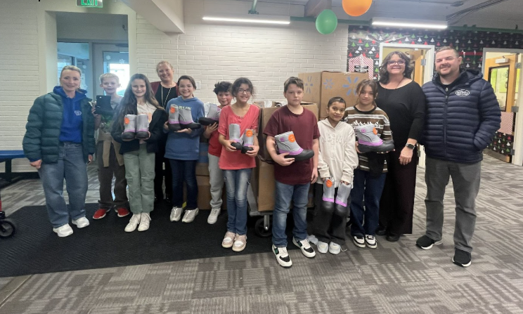 Group of students smiling while  holding snow boots.