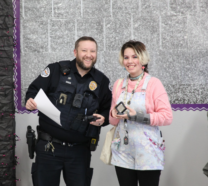 An officer and student smile for picture