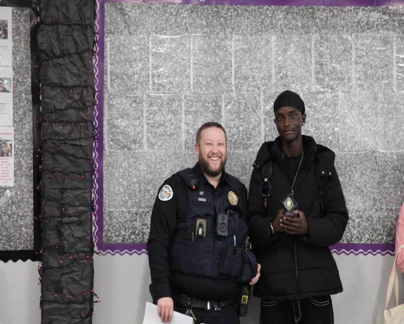 An officer and student smile for picture