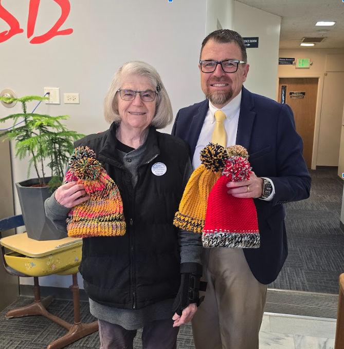Margot Wright and Superintendent Dickinson picturesdtogether holding handmade winter hats 