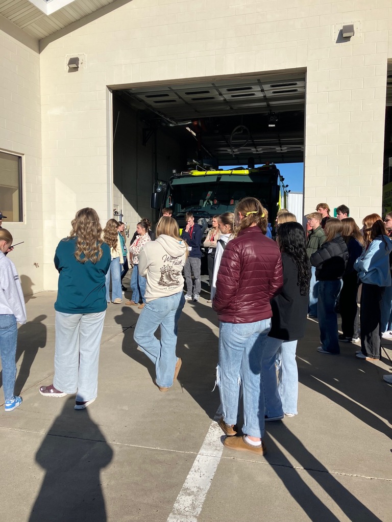 Group of students standing in front of a large, open garage door.