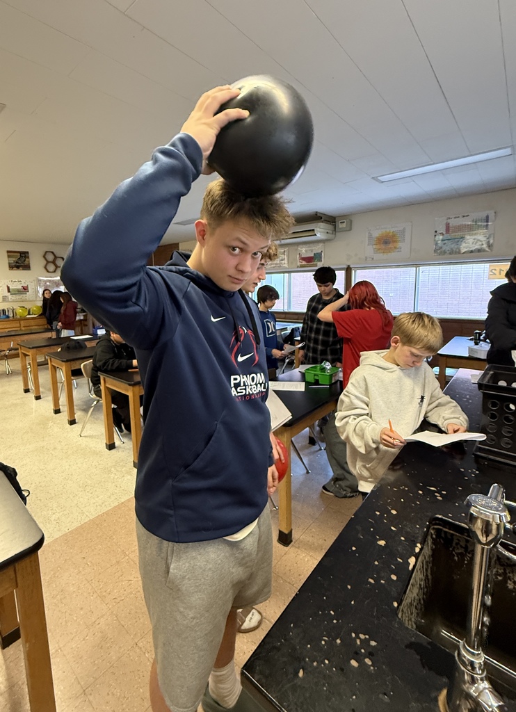 A male student rubbing a black balloon on his head.