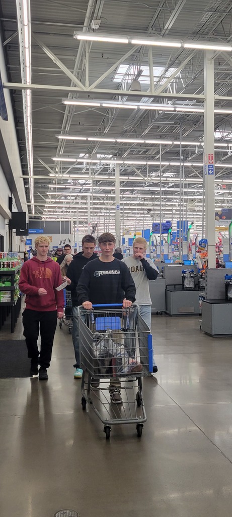 Group of boys walking out of Walmart, one pushing a shopping cart.
