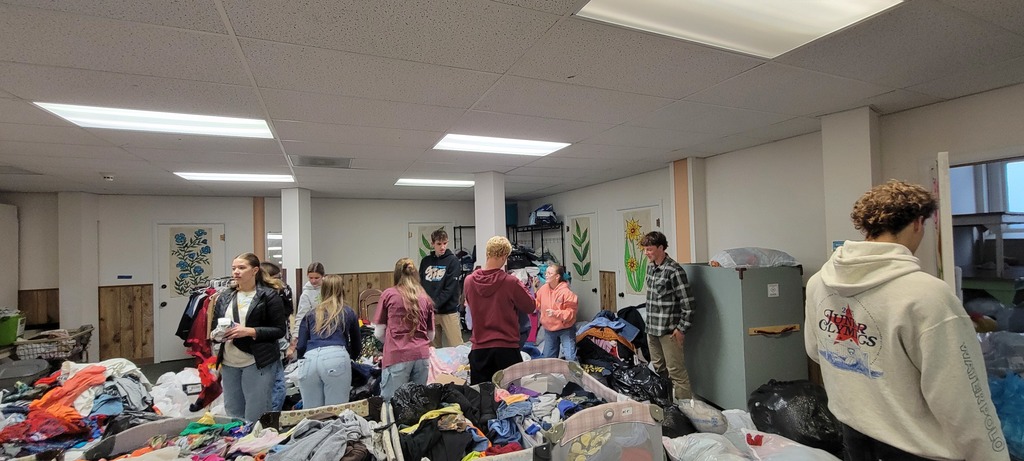 Students in room full of clothing donations