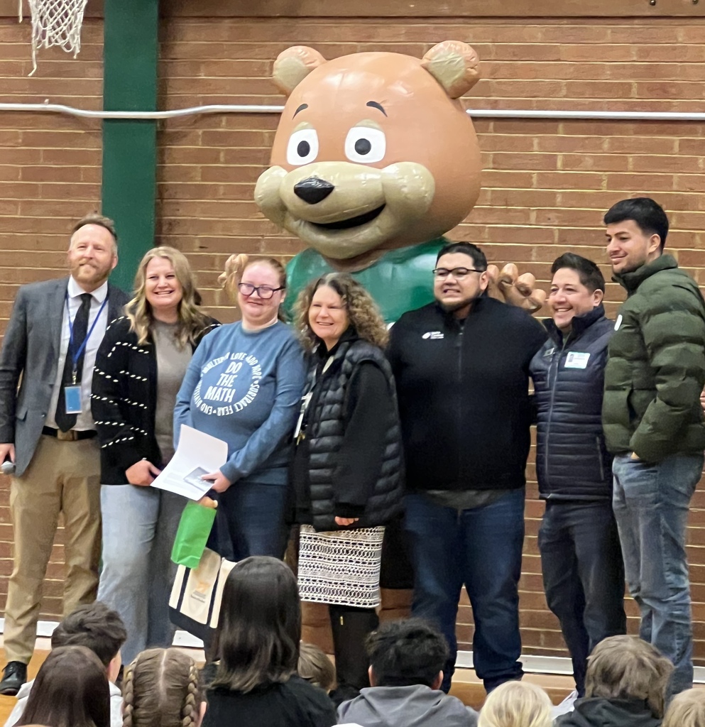a group picture of school staff members in gym with an inflatable bear behind them