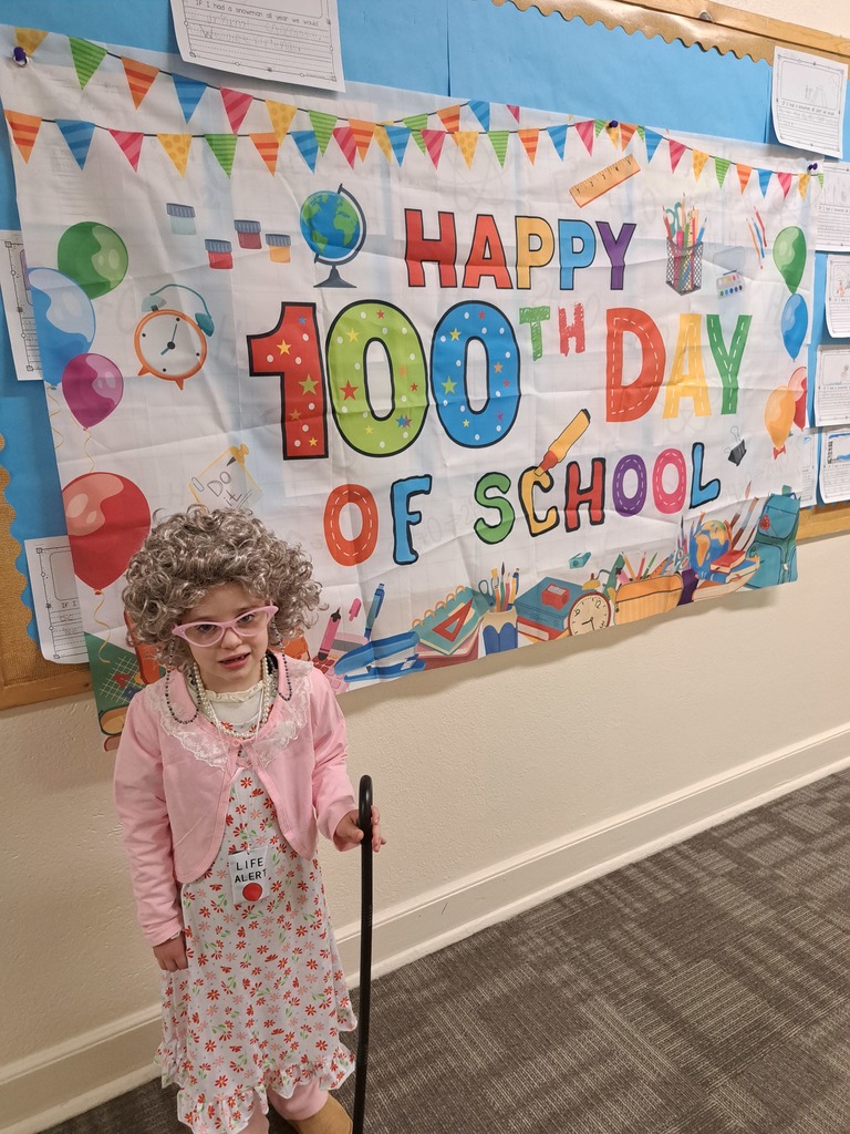girl standing in front of happy 100th day of school sign