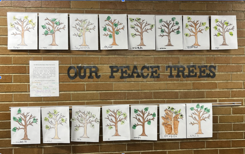 A brick wall with classwork titled "Our Peace Trees" hanging on it