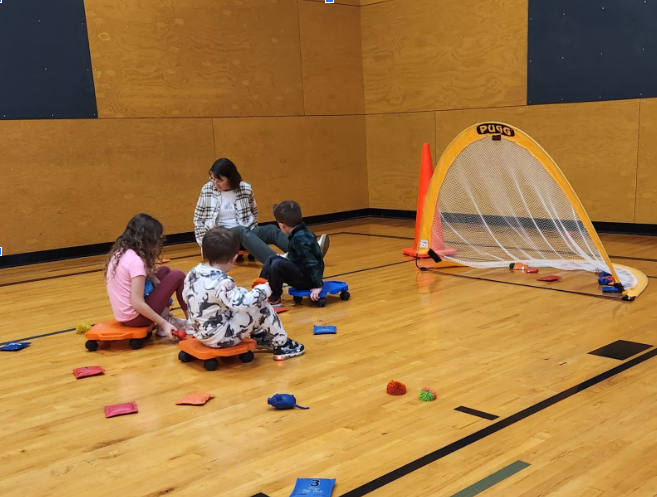 Students scooting along a gym floor playing a game