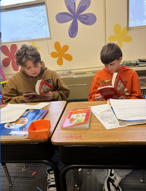 Two students reading at their desks, eagerly  earning their knighthood.