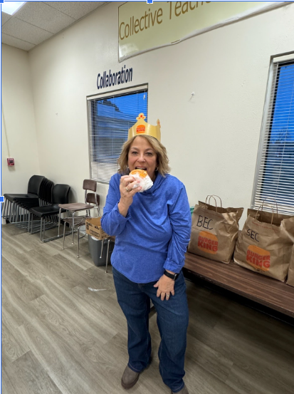 Teacher wearing a Burger King crown posing with a breakfast sandwich