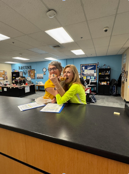 Two administrators posing playfully with breakfast snadwiches.