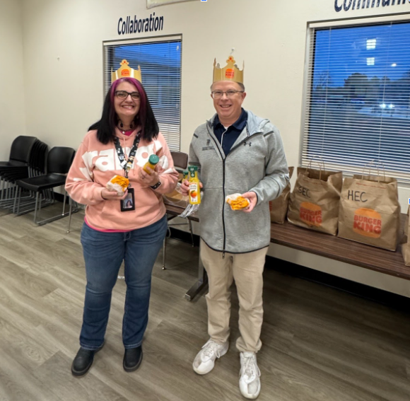 Two teachers posing with Burger King breakfast in hand.
