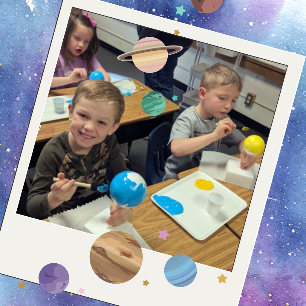 Boy sitting at desk smiling while painting a planet