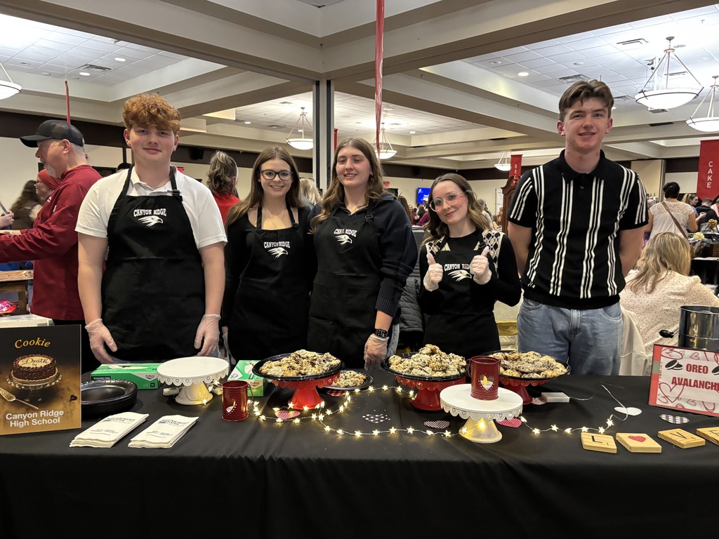 Students pictured standing behind a table displayed with treats
