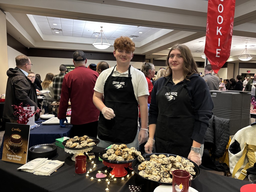 Students pictured standing behind a table displayed with treats