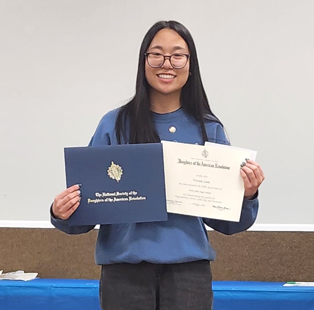 Girl with glasses holds certificates she earned